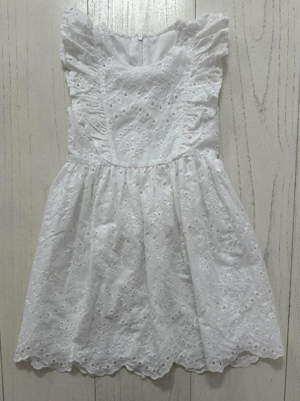 Vestido blanco con volados en las mangas y detalles de bordado y puntilla en toda la prenda. Cierre en la espalda.