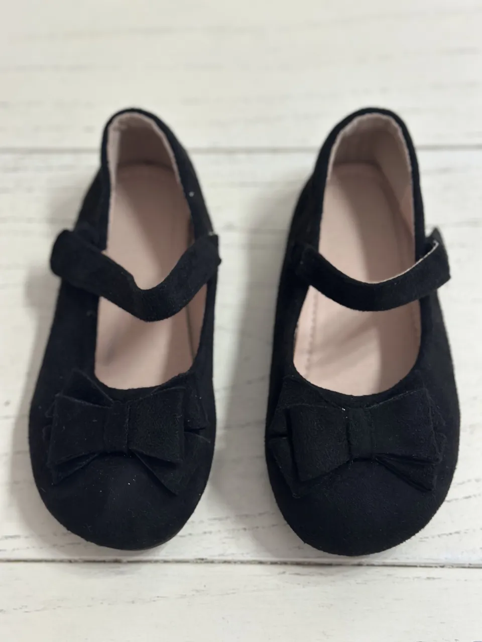 Zapatitos negros con moño y tira al tobillo.