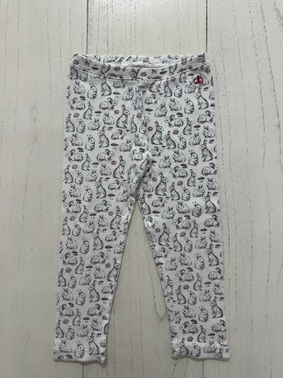 Calza blanca con estampa de conejos y hongos en gris y rosa. Tiene un pequeño bordado rojo en la cintura.