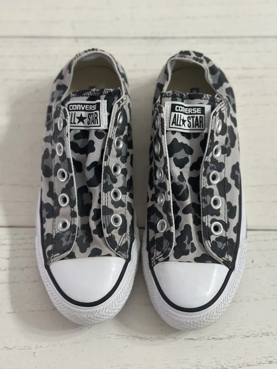 Zapatillas urbanas sin cordones con estampa animal print de leopardo en tonos grises y negros. Detalle de puntera blanca y suela de goma.