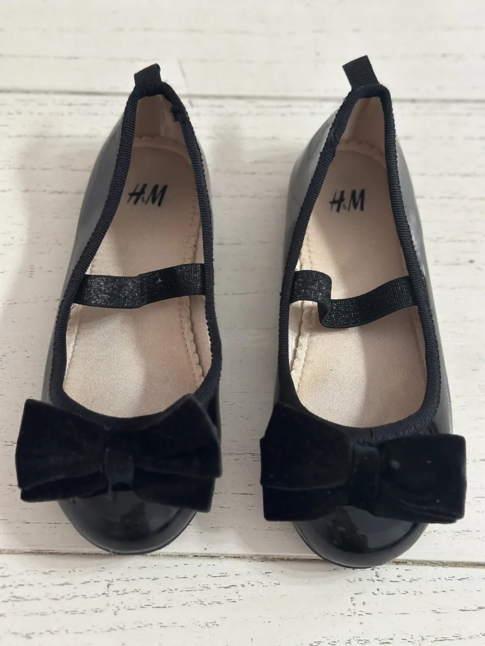 Zapatos negros para niña con lazo de terciopelo y tira elástica.