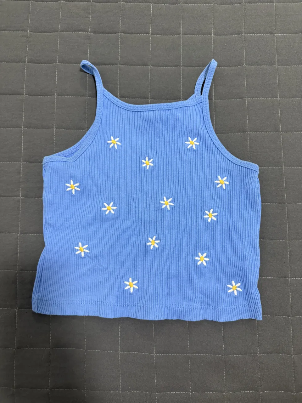 Musculosa azul con tiras finas y estampa de flores blancas bordadas.