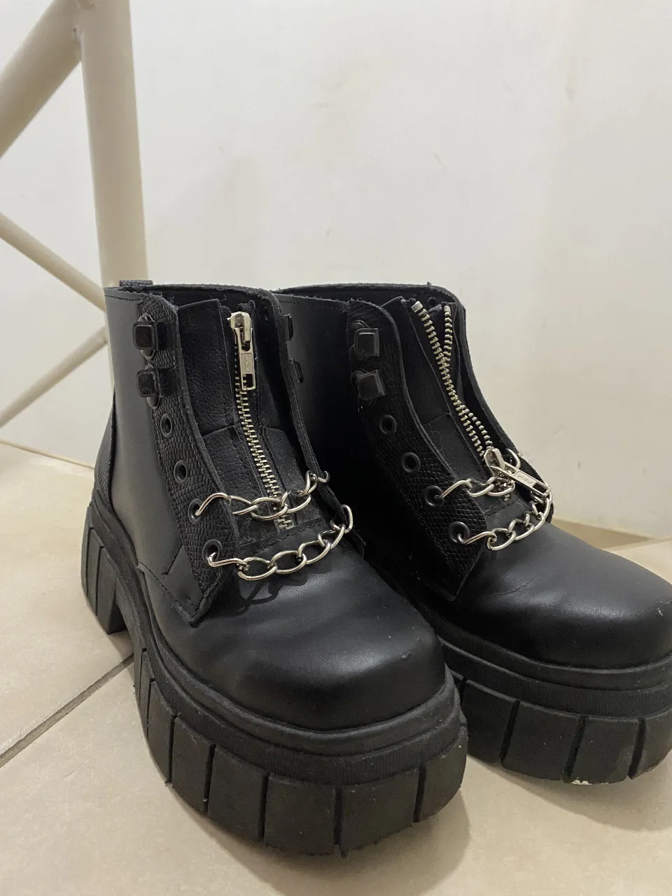 Borcegos negros de cuero sintético con plataforma y detalles de cadenas. Estilo rocker y urbano, ideales para un look audaz y moderno.