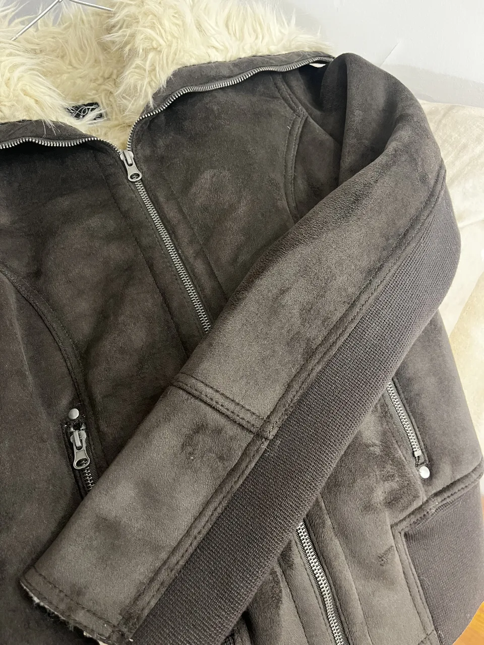 Campera de mujer en gamuza marrón con cuello de piel sintética. Detalles de cierre y ajuste en mangas. Ideal para un look casual y moderno.
