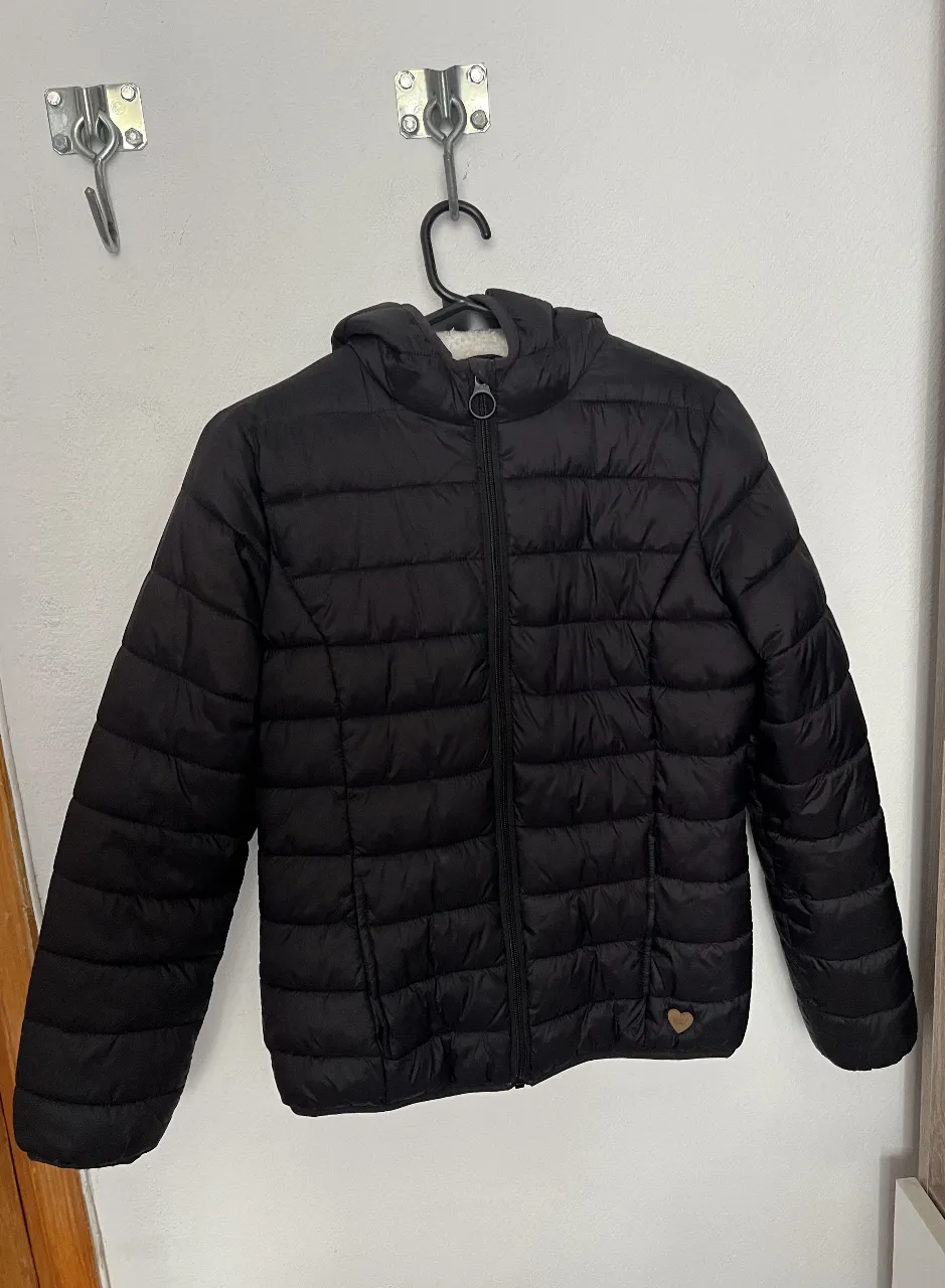 Campera acolchada negra para niña, con capucha y forro de peluche en el interior. Ideal para el invierno, con cierre y detalles de corazón.