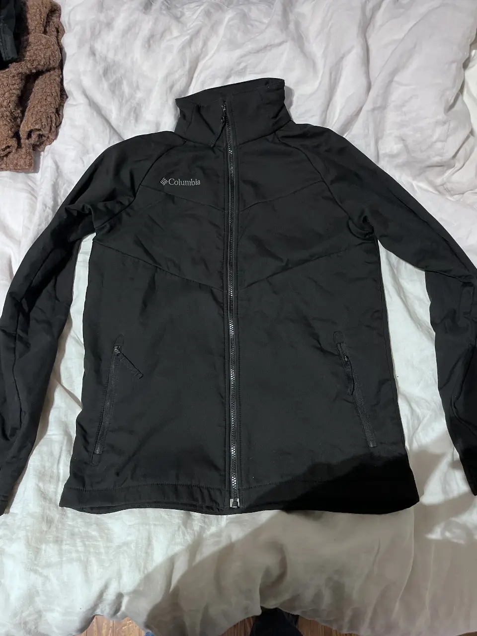 Campera deportiva Columbia negra con cierre y cuello alto. Ideal para actividades al aire libre o uso diario. Talle juvenil.