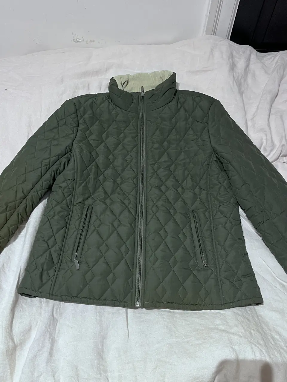 Campera verde militar acolchada con cuello alto y cierre. Ideal para el invierno, con bolsillos y forro interior.