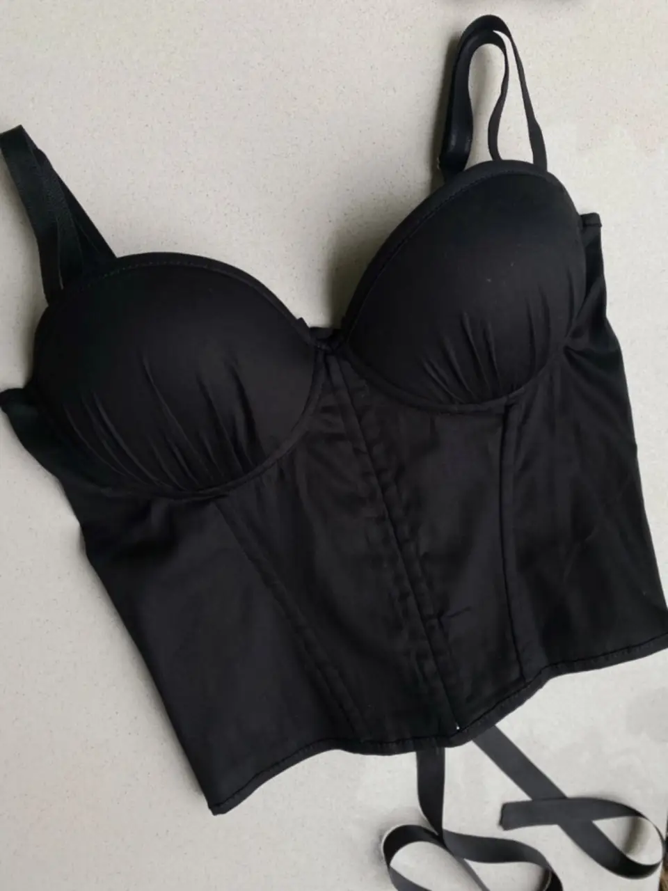 Top corset negro con ballenas, breteles regulables y detalle de lazo en los hombros. Ideal para un look elegante y sensual.