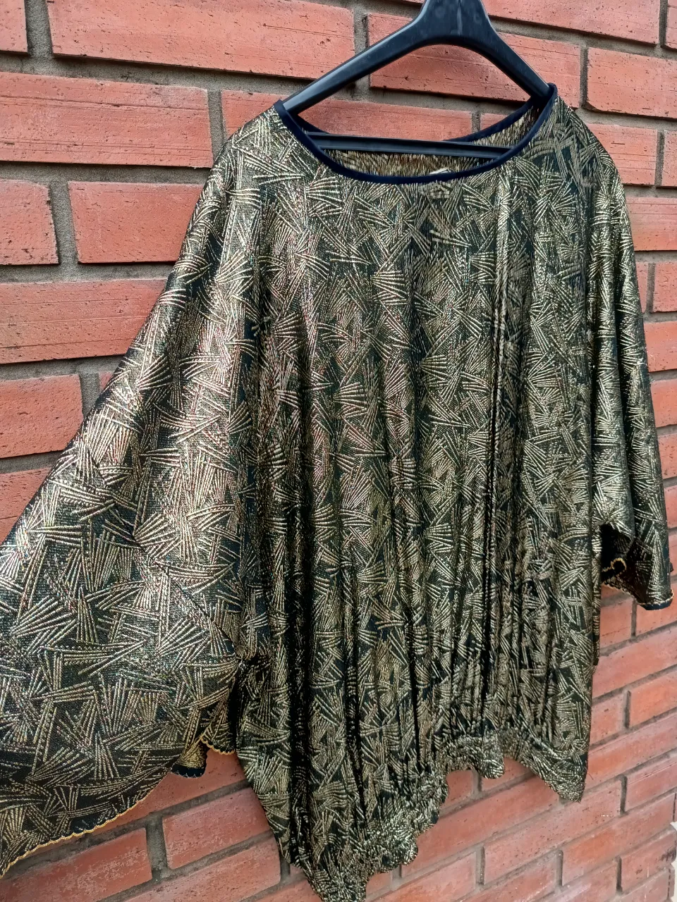 Blusa con estampado abstracto en dorado y negro. Posee cuello redondo y mangas largas.