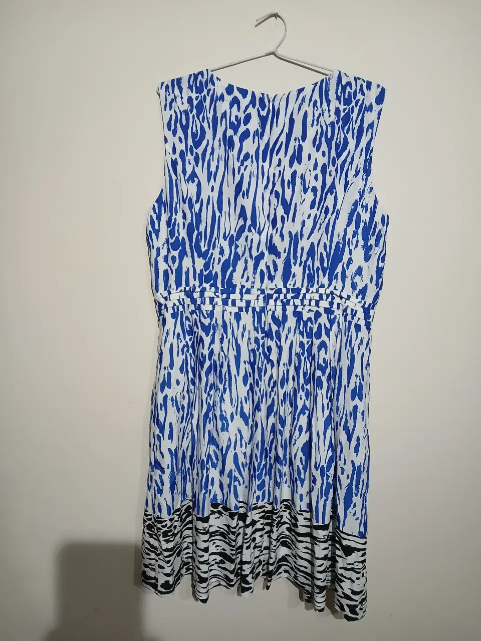 Vestido midi sin mangas con estampado abstracto en tonos azules y blancos. Cintura entallada con detalle de fruncido y falda con estampado de cebra en el borde. Ideal para un look fresco y moderno.