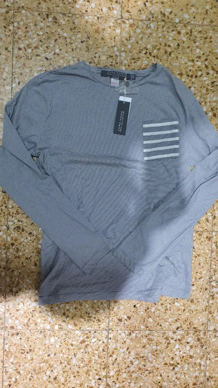 Remera manga larga de hombre, a rayas horizontales grises y blancas, con bolsillo en el pecho. Marca Zara Home.