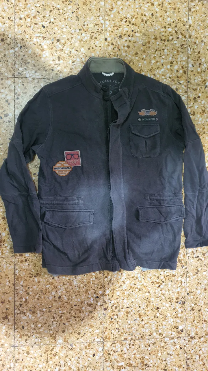 Campera tipo bomber de hombre, color gris oscuro con detalles de parches. Talle M. Ideal para un look casual y urbano.