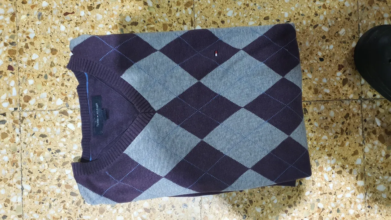 Clásico sweater chaleco Tommy Hilfiger para hombre, con diseño de rombos en tonos grises y violetas. Ideal para un look preppy y elegante.