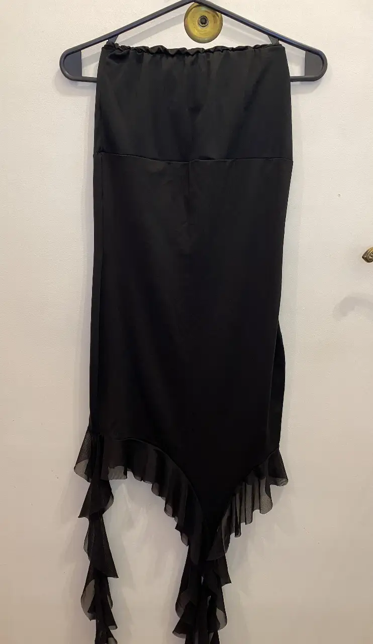 Vestido mini negro con detalle de volados asimétricos en la falda. 
