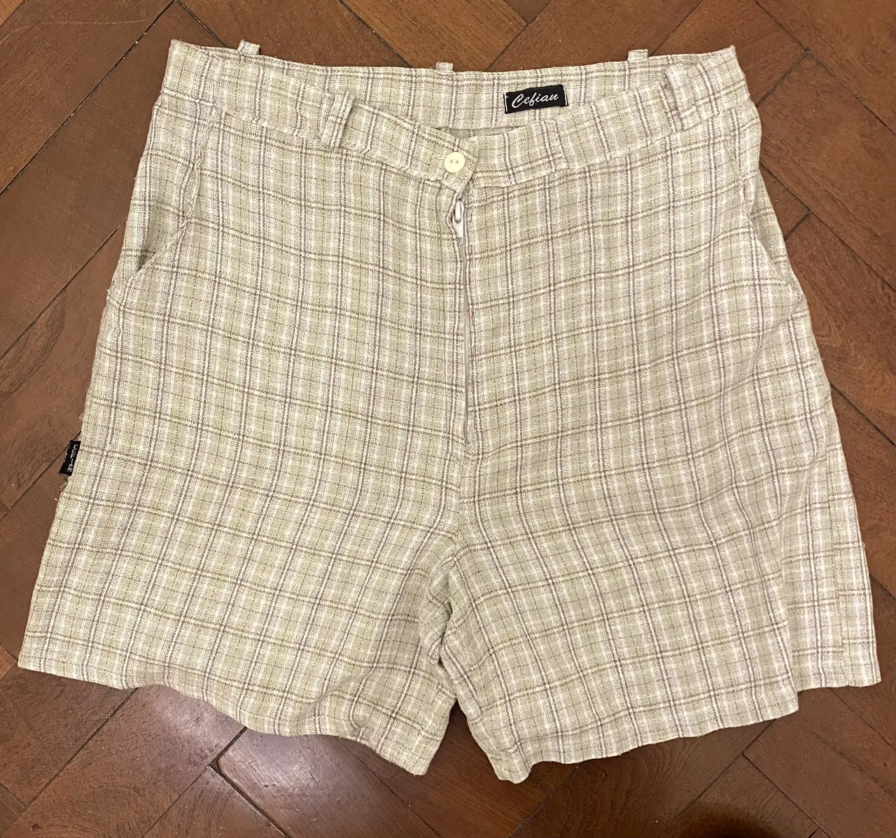 Short de mujer tiro alto con estampado a cuadros en tonos crudos y marrones. Ideal para un look casual y fresco. Medidas aproximadas (tomadas en plano): 37 cm ancho de cintura, 42cm largo.