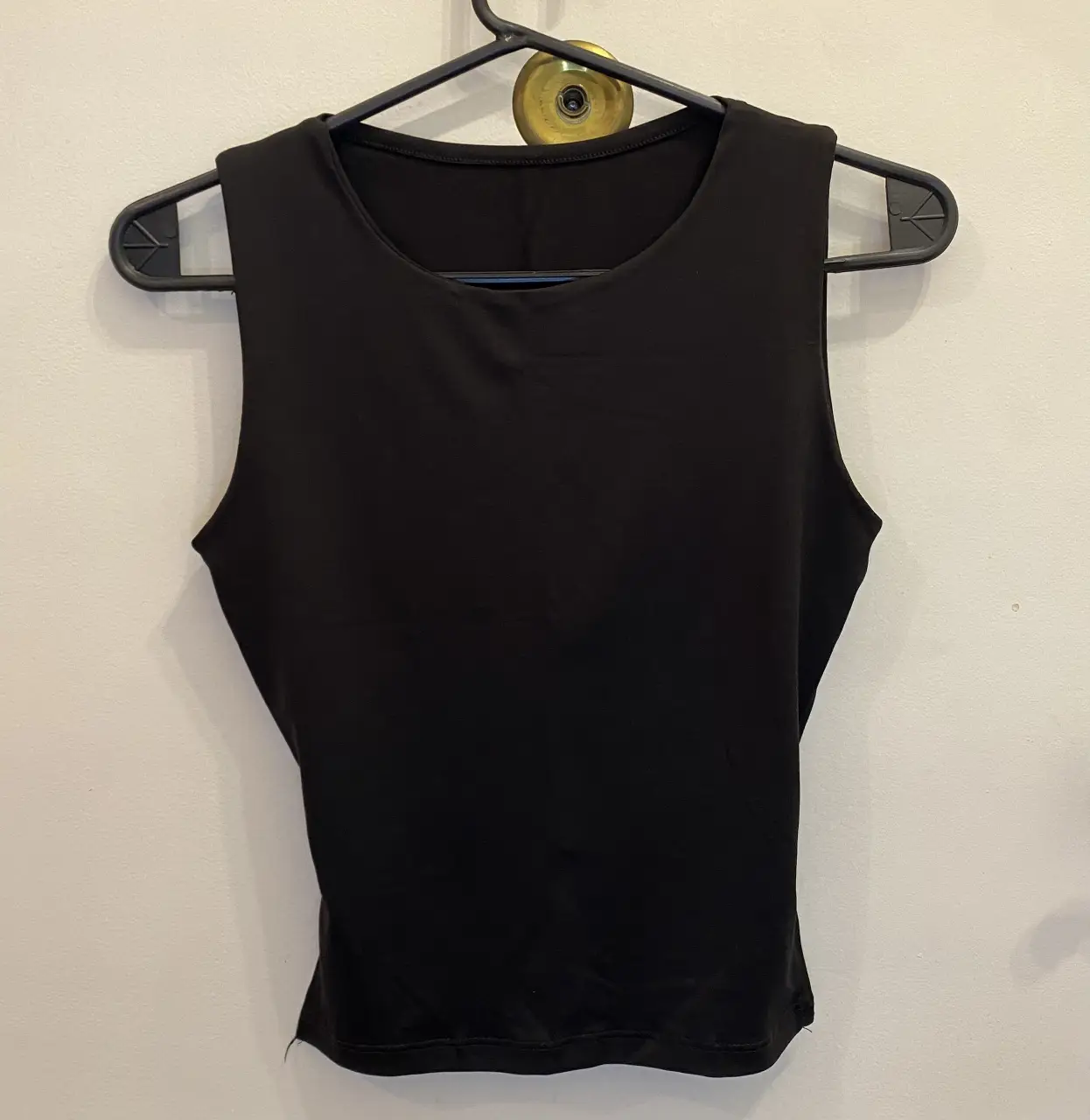 Top negro sin mangas con espalda descubierta y detalle de hebilla. Medidas aproximadas (tomadas en plano): 35cm ancho, 45cm largo