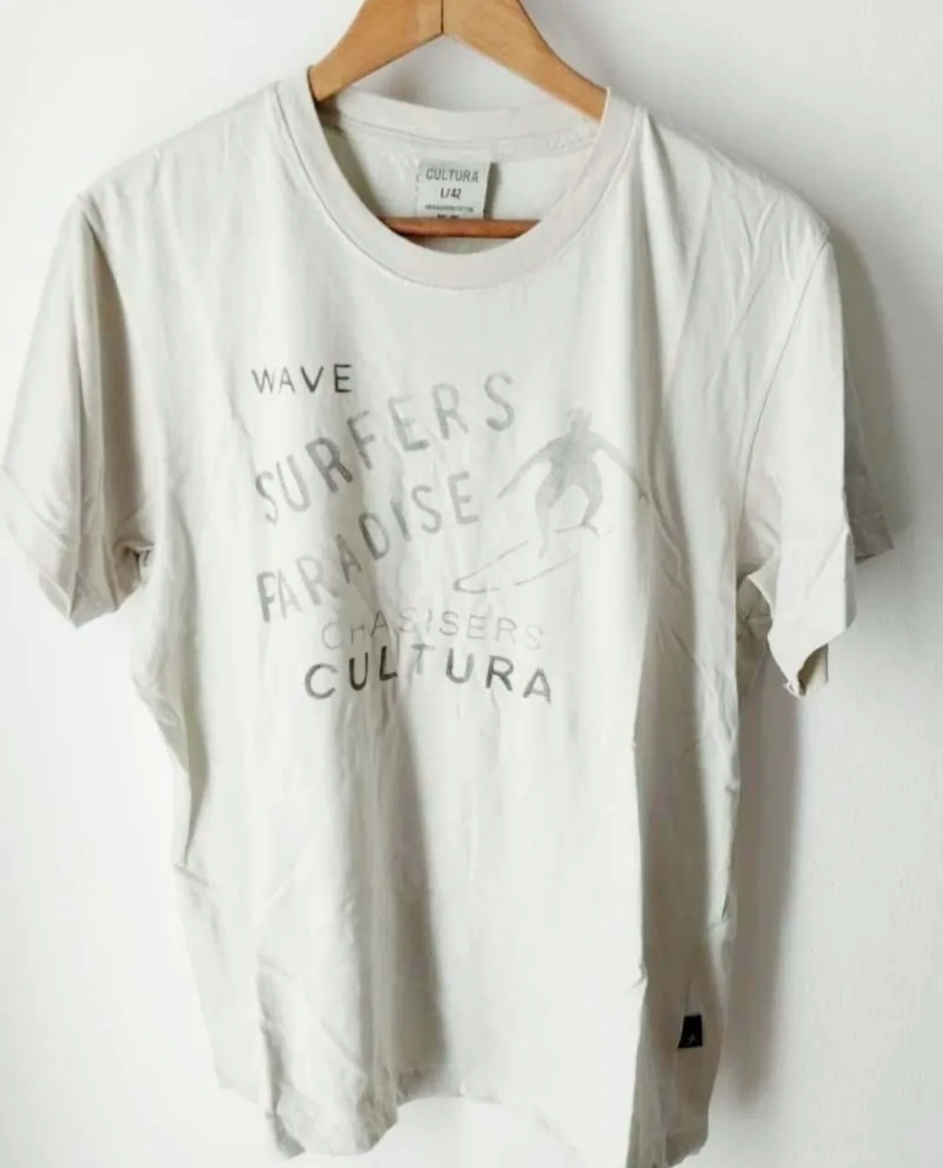Remera de algodón color crudo con estampa de surf y texto "WAVE SURFERS PARADISE CHASERS CULTURA".
