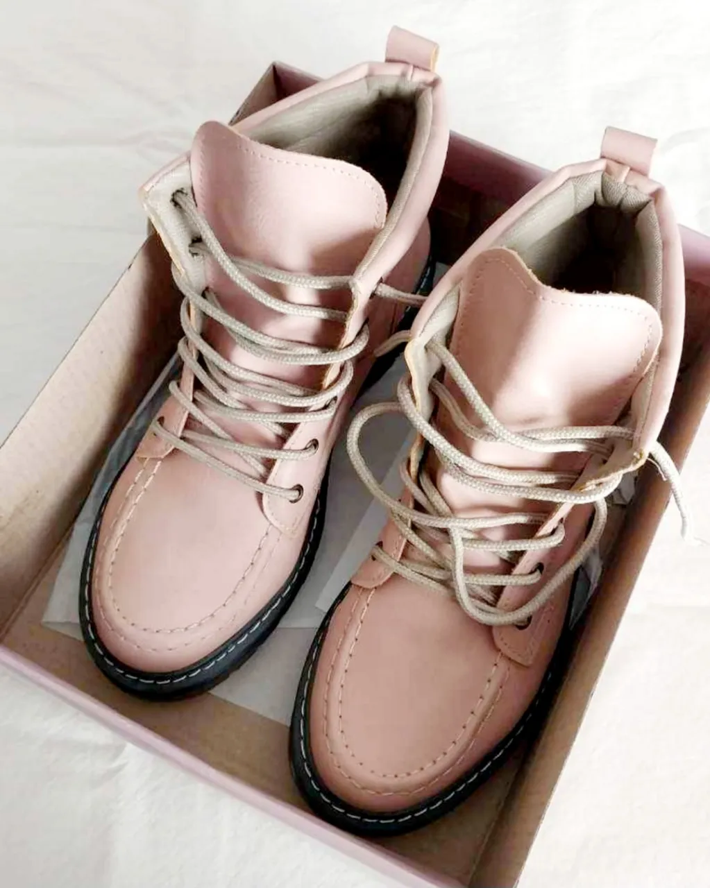 Botitas de cuero color rosa pálido con cordones. Suela negra.