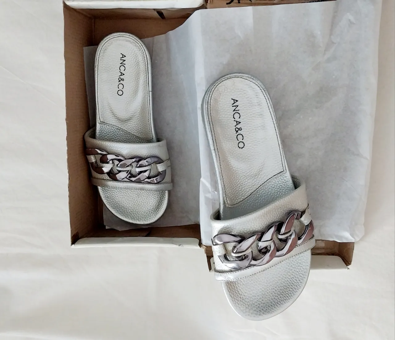 Sandalias plateadas con detalle de cadena grande en la tira superior. Perfectas para un look canchero y moderno.