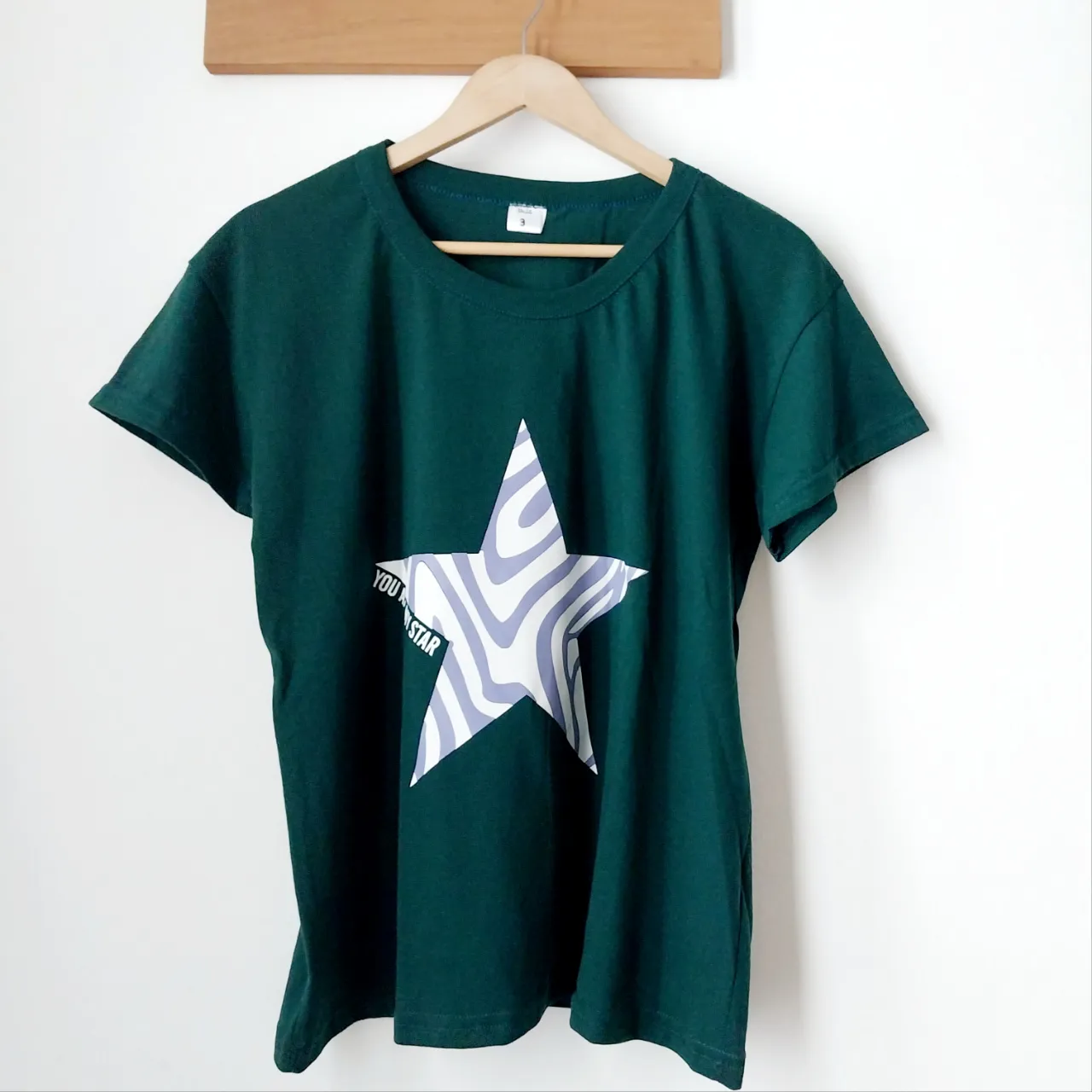 Remera manga corta de color verde oscuro con estampa de estrella blanca y violeta con la frase "YOU ARE MY STAR".
