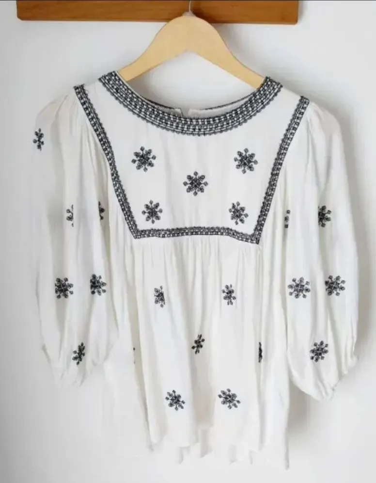 Blusa blanca con bordados en negro, estilo boho. Ideal para un look casual y fresco.