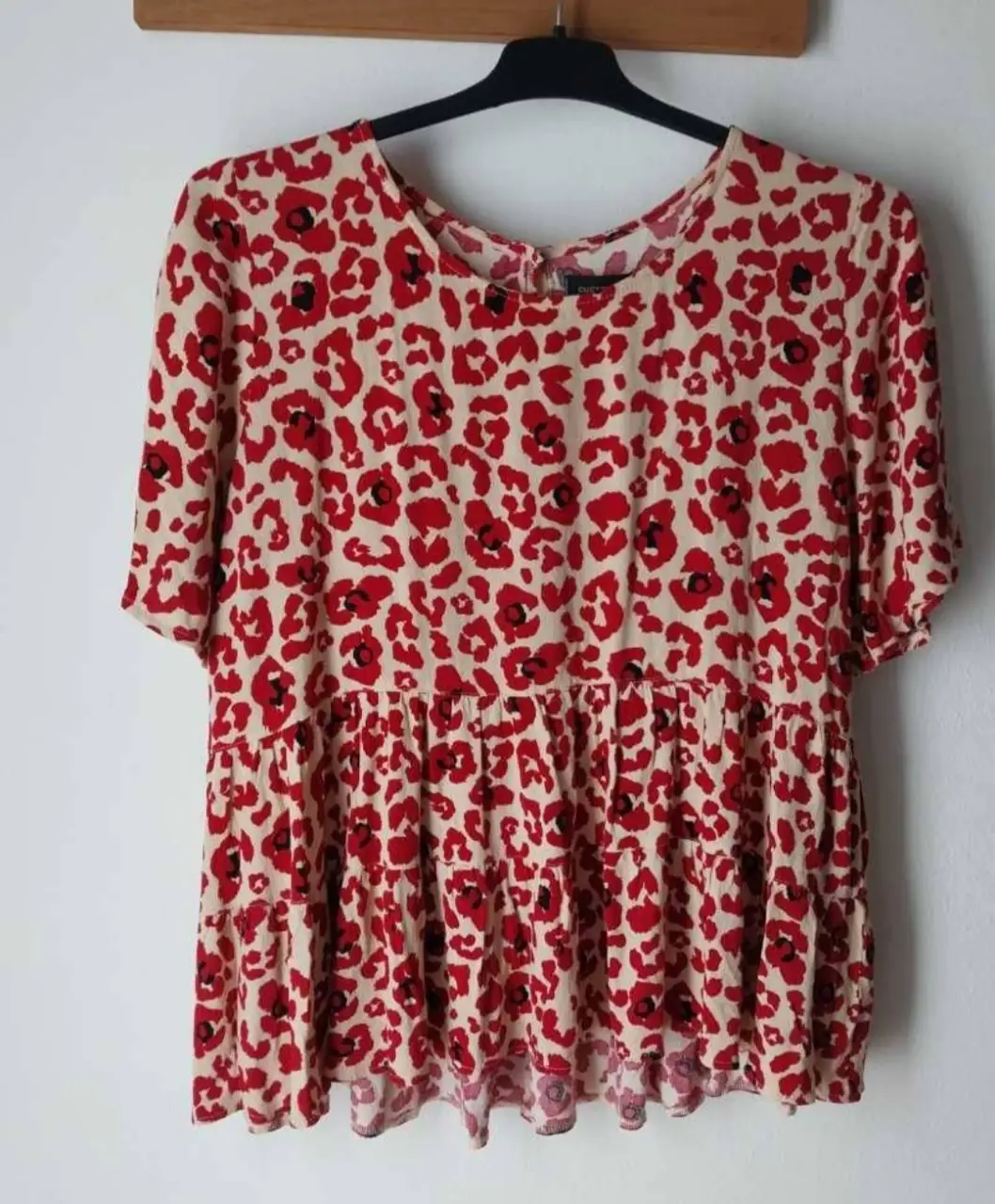Vestido midi con estampado de flores rojas sobre fondo crudo. Corte holgado y diseño con volados. Ideal para un look fresco y femenino.