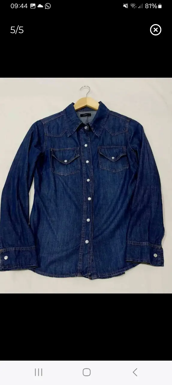 Camisa de jean azul oscuro, con dos bolsillos delanteros y botones de broche nácar. Ideal para un look casual y moderno.