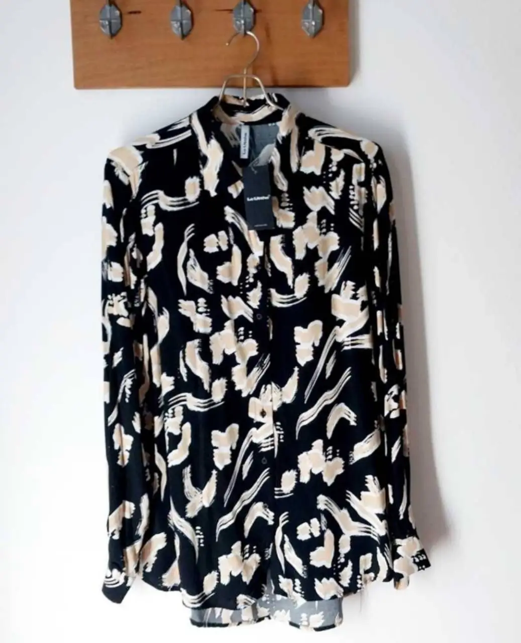 Camisa estampada de manga larga para mujer, con estampado abstracto en tonos negro y crudo. Ideal para un look casual o de trabajo.