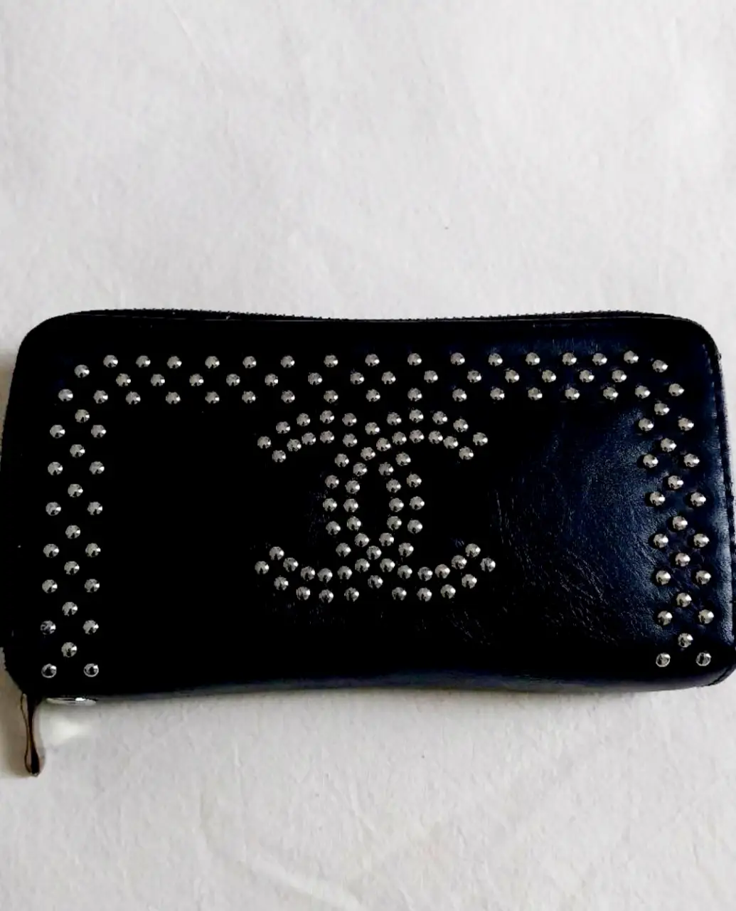 Billetera negra con tachas plateadas y el logo de la marca. Diseño elegante y moderno, ideal para llevar tus esenciales con estilo.