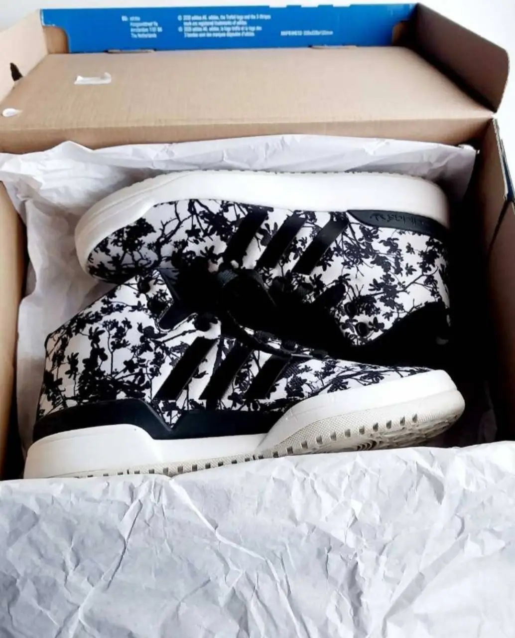 Zapatillas Adidas con estampado floral en blanco y negro. Diseño moderno y cómodo, ideales para un look casual y urbano.plantilla 24cm