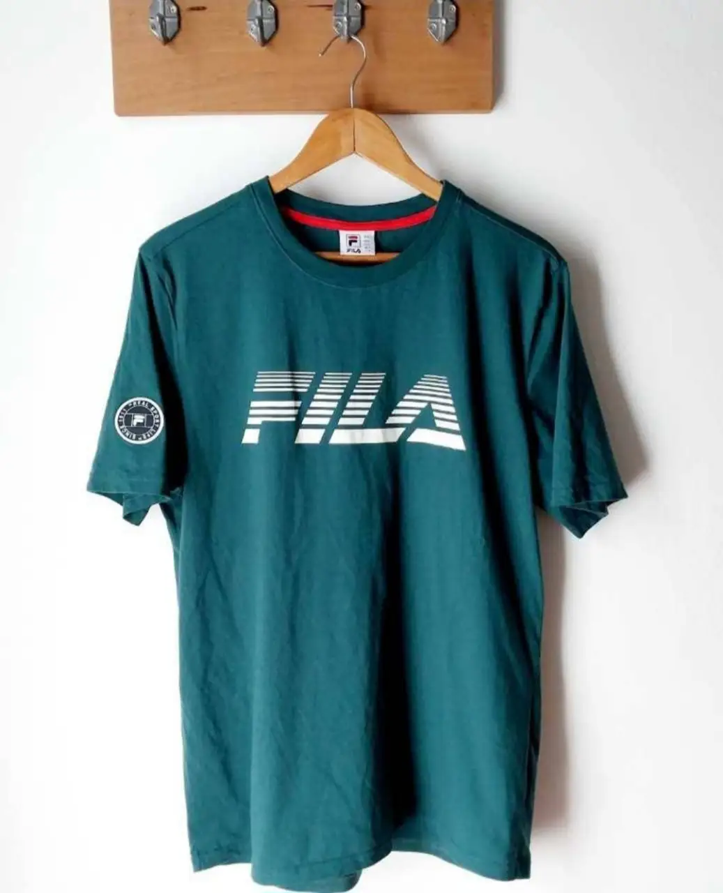 Remera Fila de hombre, color verde oscuro con logo blanco en el frente. Diseño deportivo y casual, ideal para el día a día.