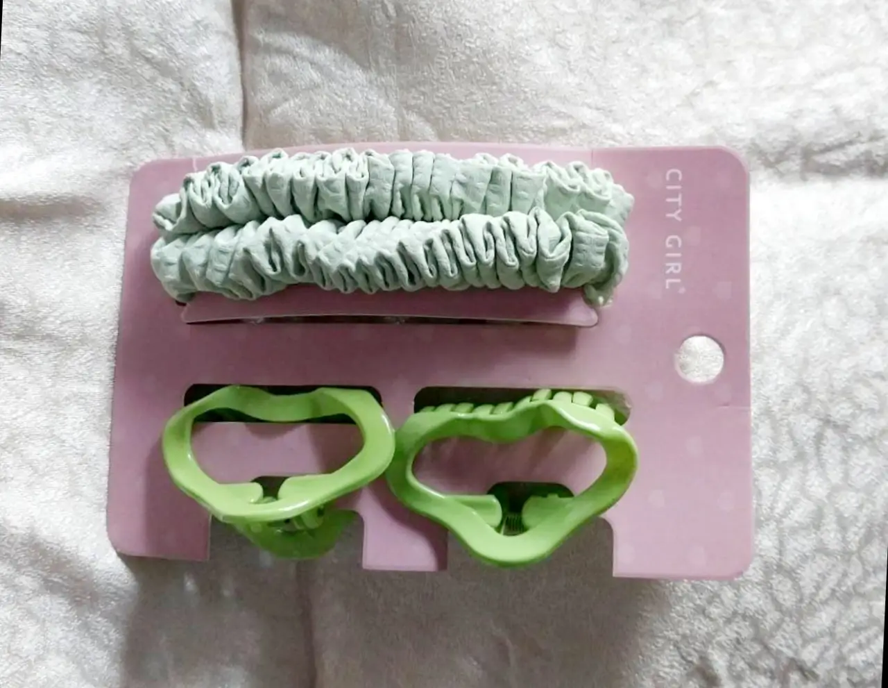 Set de accesorios para el pelo, que incluye dos hebillas en forma de labio y una cinta elástica para el cabello, todo en un tono verde claro.