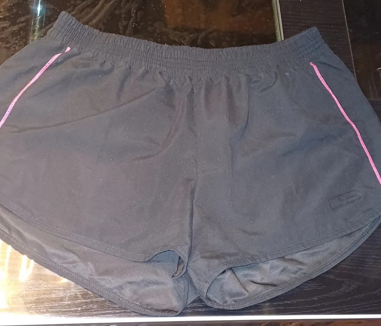 Short deportivo negro con detalles en rosa. Ideal para running y entrenamientos. Cómodo y ligero. cintura elastizada tomada en plano de in extremo al otro 36cm. estirada cede hasta 46cm. cadera tomada en plano 57cm 
largo delantero 29cm largo trasero 36cm tiro delantero 28.5 cm. tiro trasero 37.5 cm.   estado excelente. 