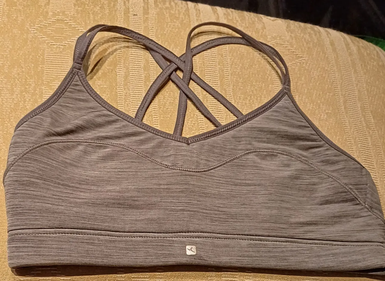 Top deportivo gris con diseño cruzado en la espalda. Ideal para actividades de bajo impacto. medidas: contorno tomado en plano 33cm osea 66 completo.  excelente estado. 