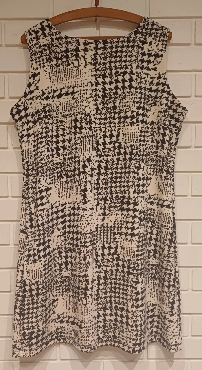 Vestido corto sin mangas con estampa "houndstooth" y detalles de diseño. Ideal para un look casual y moderno.