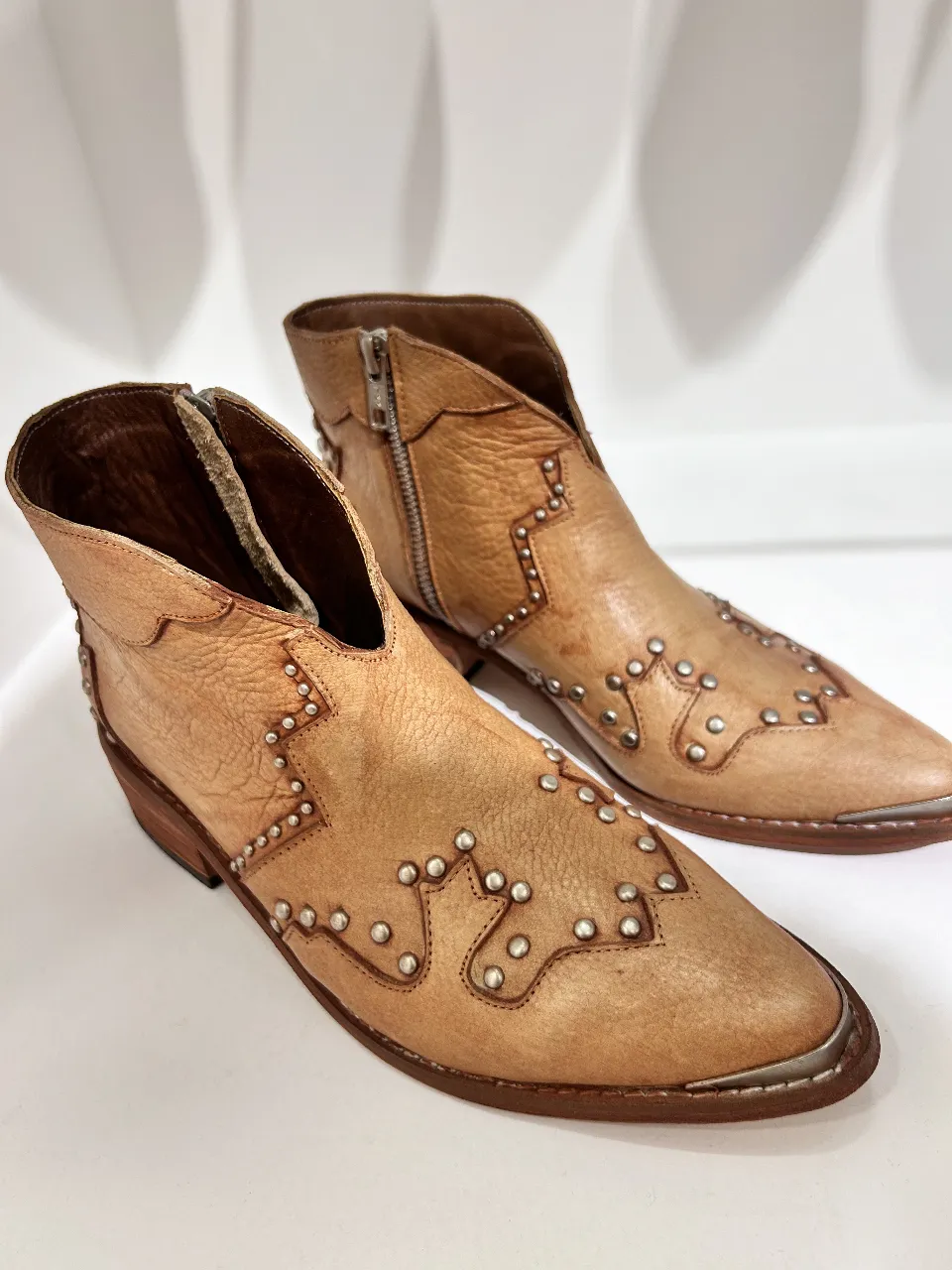 Botines de cuero marrón con detalles de tachas plateadas. Diseño estilo cowboy con cierre lateral y puntera reforzada. Ideales para un look casual y con onda.