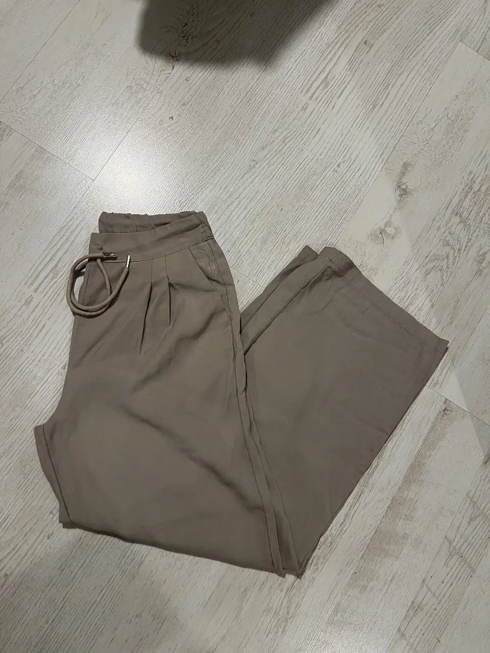 Pantalón sastrero de mujer, color khaki. Tiro alto, con cintura elastizada y cordón para ajustar. Bolsillos laterales y pinzas delanteras. Talle 38.