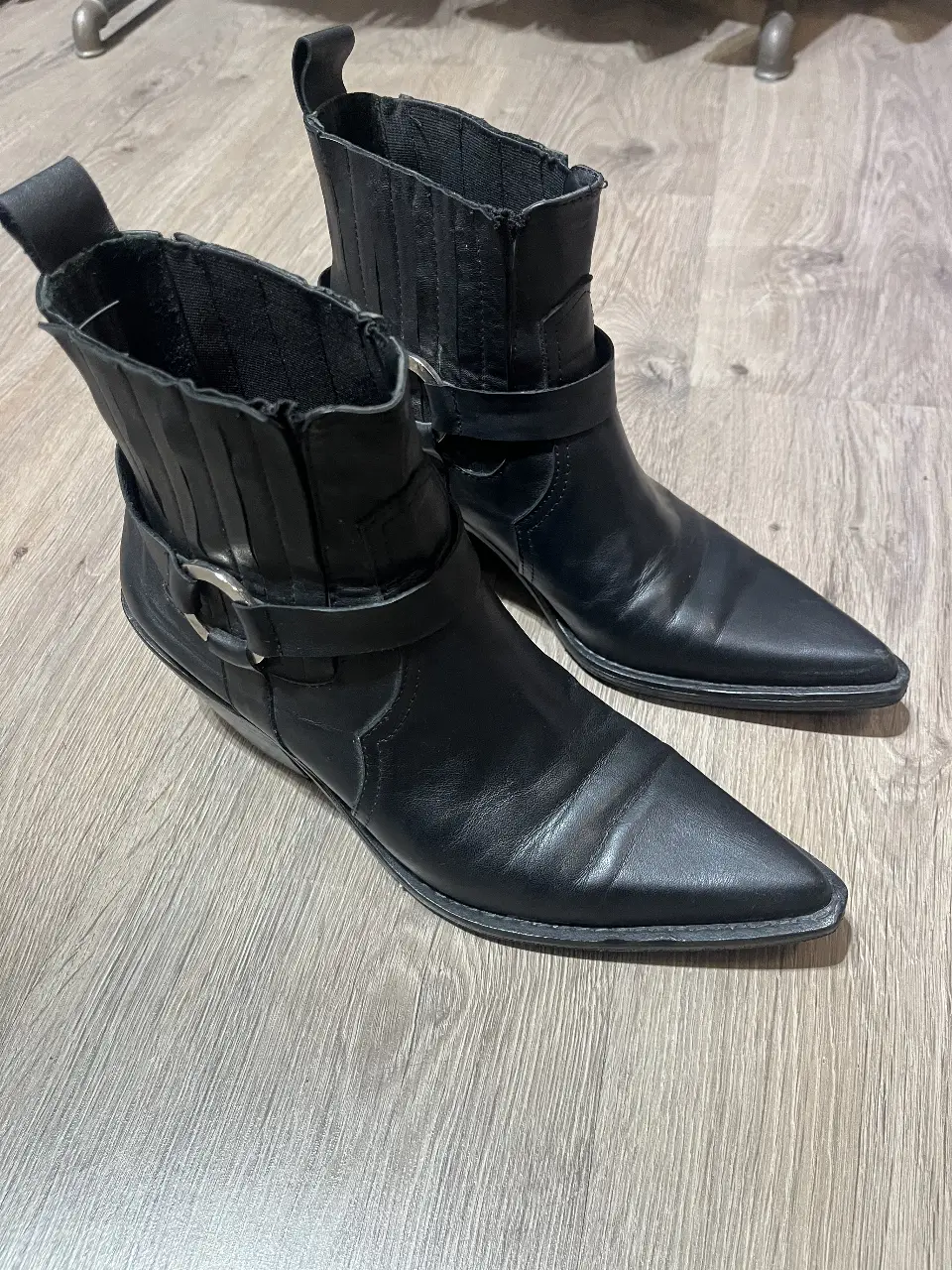Botines negros de cuero con punta fina y hebilla en el tobillo. Estilo rocker y elegante, ideales para un look de salida o fiesta.