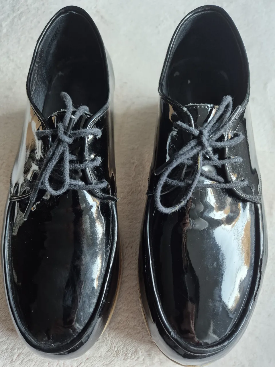 Zuecos de plataforma negros con cordones. Diseño de charol brillante y suela de madera.