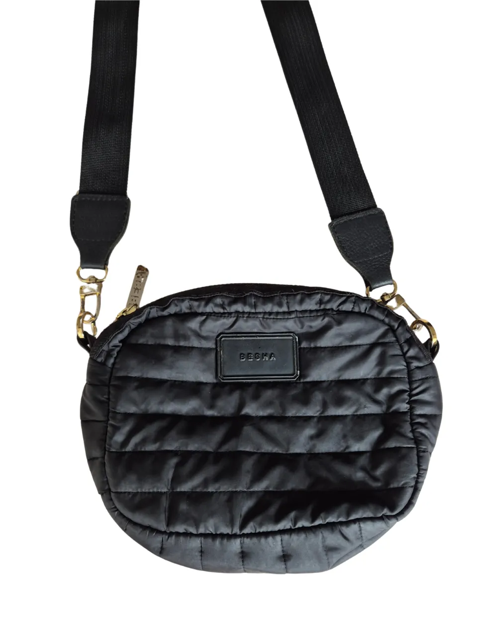 Bandolera acolchada negra con correa ajustable. Ideal para llevar tus esenciales con estilo y comodidad. Perfecta para un look casual y moderno.
