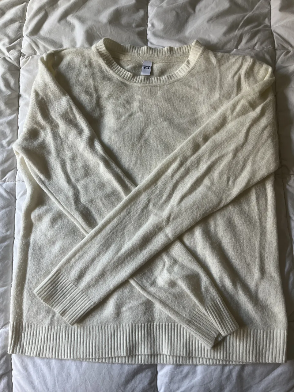 Sweater de VER, de lana color crudo con cuello redondo y mangas largas. Puños y cintura con terminación acanalada. 