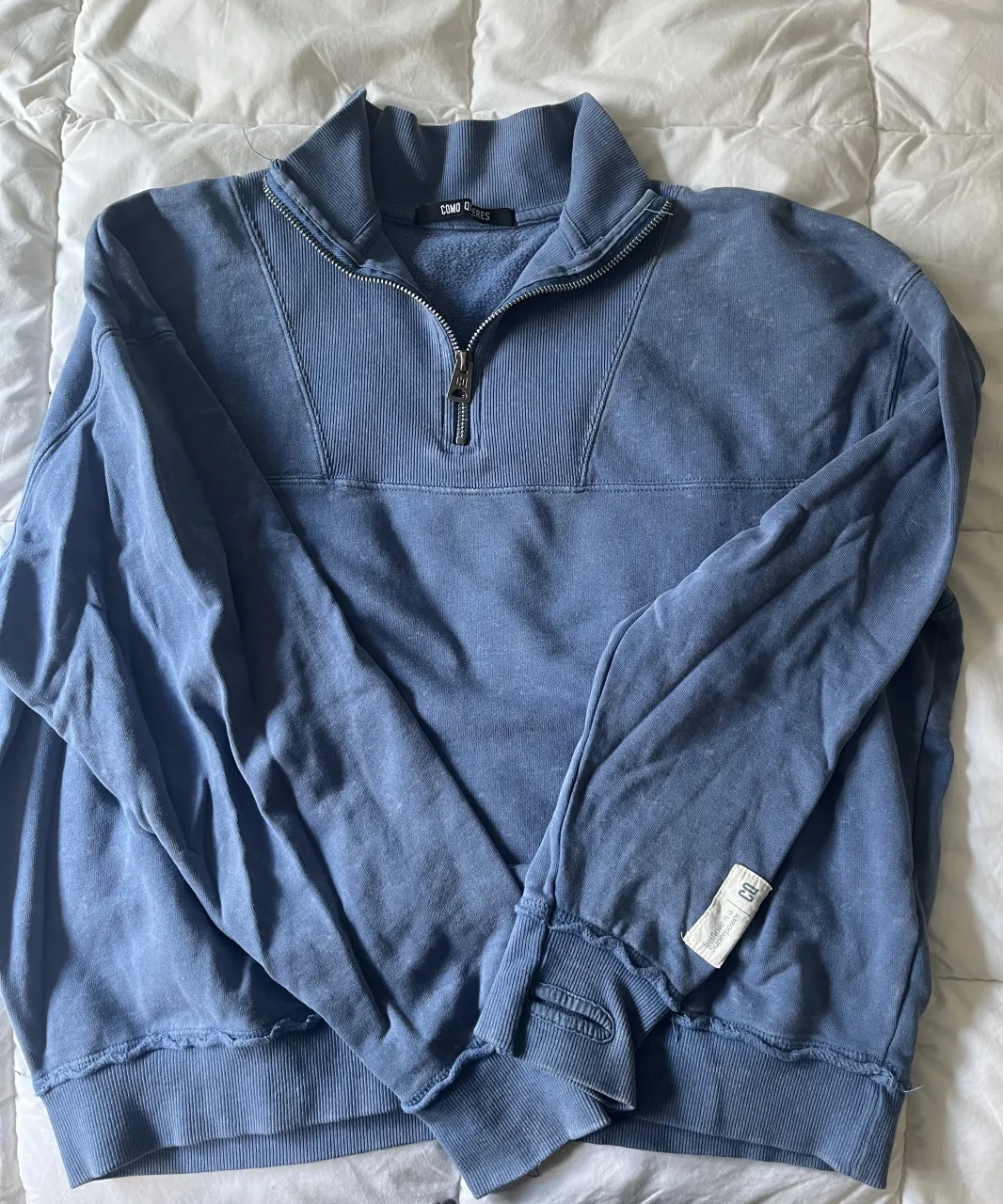 Buzo azul de algodón con cuello alto y cierre metálico de 1/4. Posee detalles de costuras en el frente y puños y cintura de ribb.