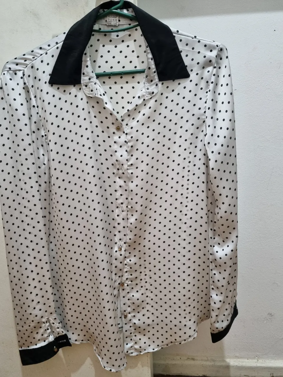 Blusa blanca con lunares negros y cuello negro. Ideal para un look elegante y sofisticado.