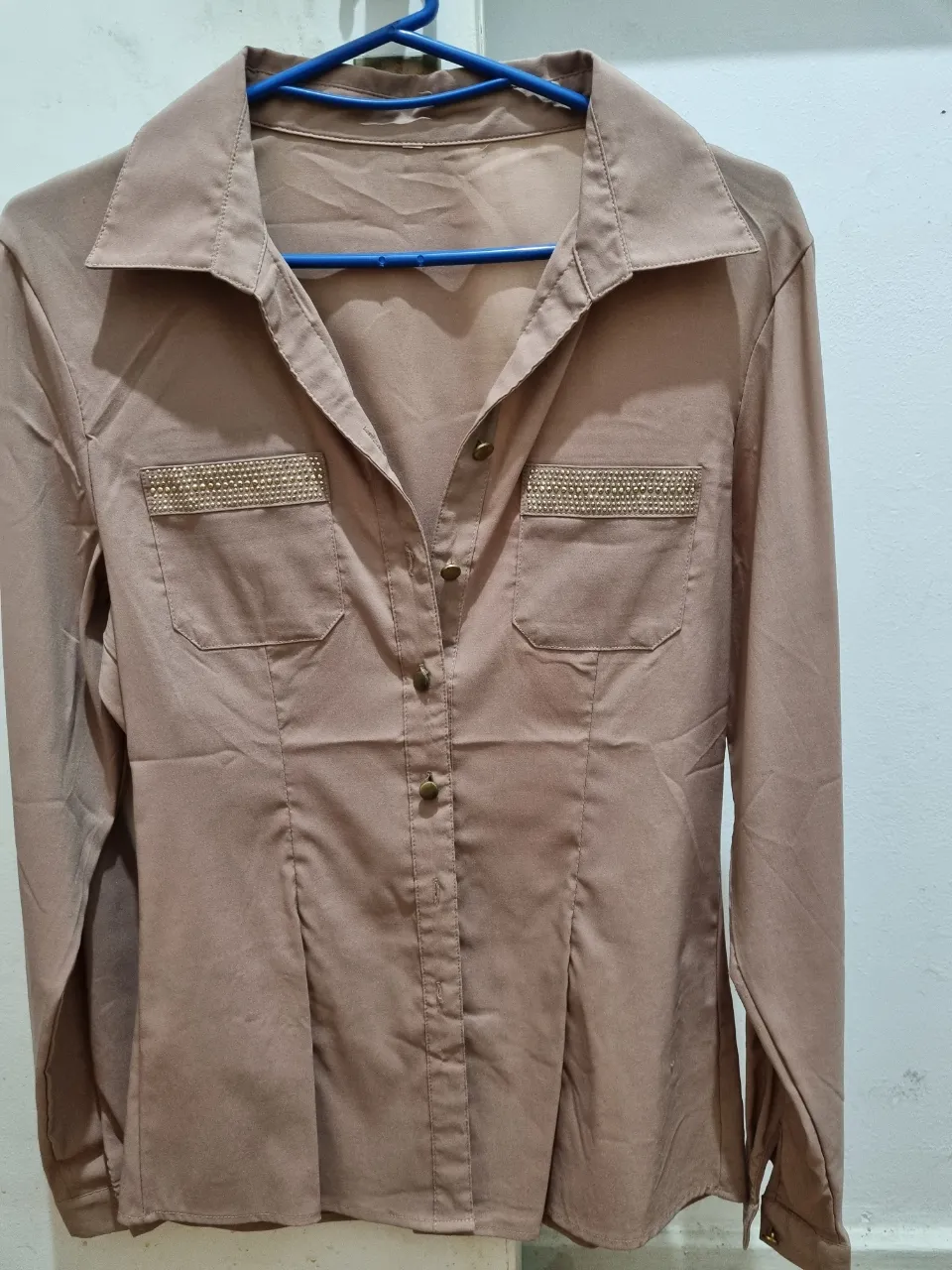 Blusa manga larga color marrón con detalles dorados en bolsillos. Ideal para un look elegante y sofisticado.