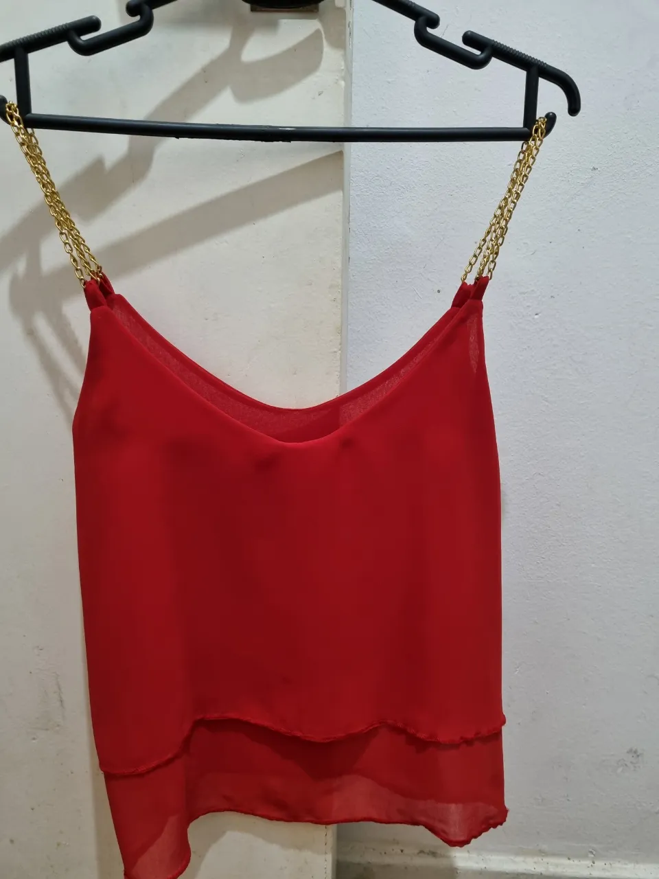 Remera roja con tiras doradas de cadena, ideal para una salida o fiesta. Diseño elegante y moderno.