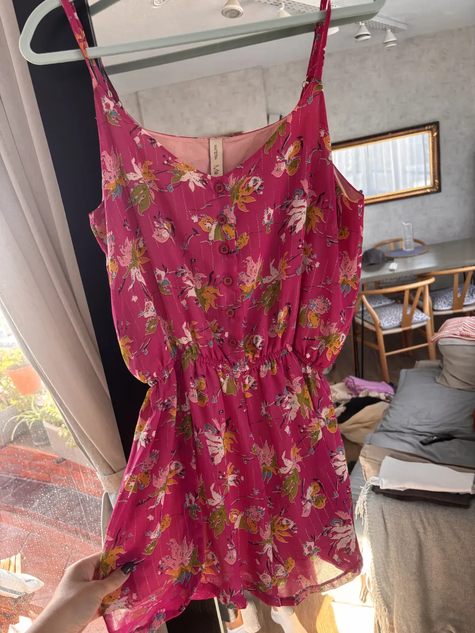 Mono corto súper femenino con estampado floral vibrante en tonos fucsia, blanco, verde y amarillo. Posee breteles finos, cuello en V y botones en la parte superior. La cintura es elastizada, lo que le da un calce cómodo y favorecedor. Ideal para un look fresco y canchero en días soleados.