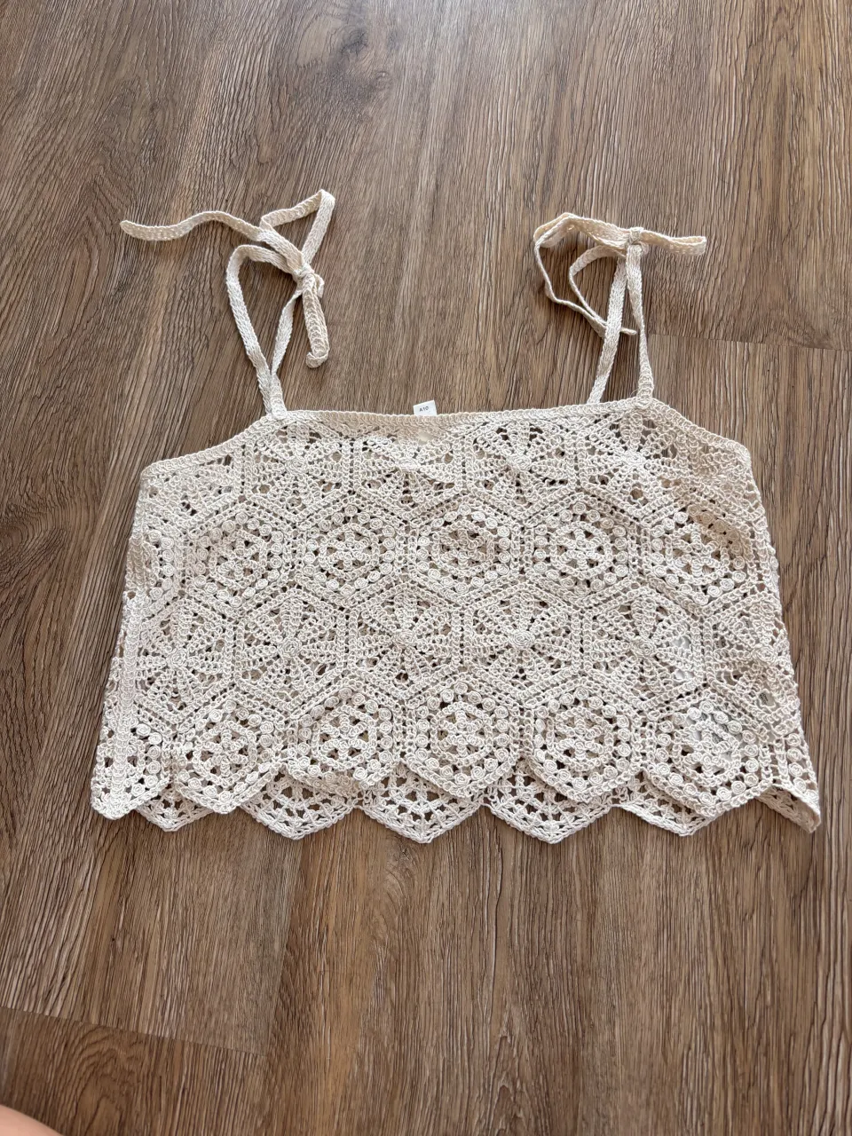 Top H&M tejido al crochet en color crudo, con breteles finos y detalle de puntilla en el borde inferior. Ideal para un look boho chic o playero.