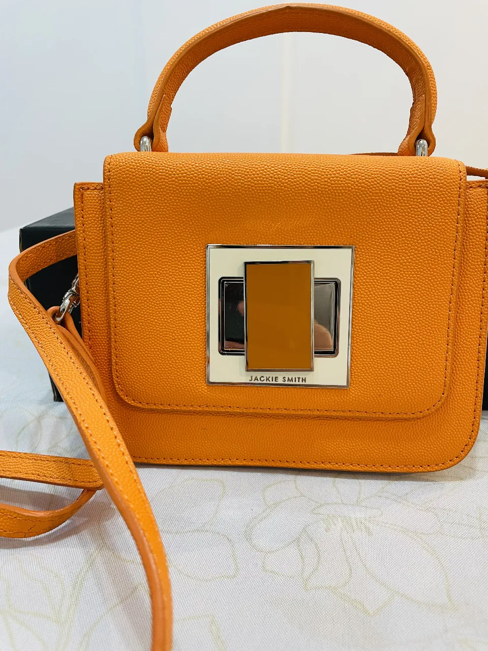 Cartera Jackie Smith naranja con manija superior y correa larga. Modelo pocket. Cierre con detalle metálico en el frente. Por dentro forrada y tiene bolsillito con cierre. Tiene 1 SOLO USO! Está impecable. Es de un naranja hermoso.