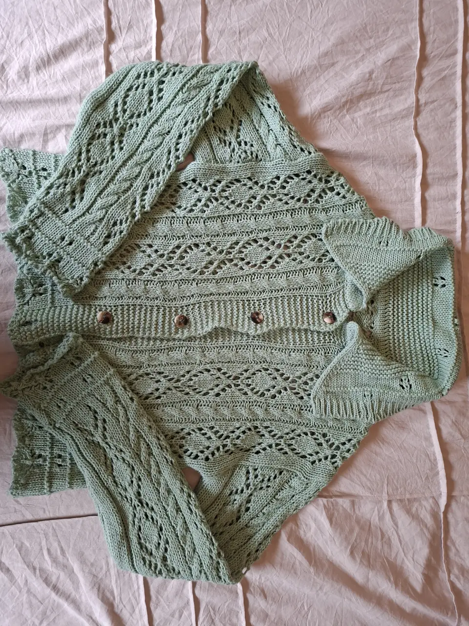 Cardigan tejido a mano en color verde claro, con detalles calados y botones. Ideal para un look artesanal y cómodo.