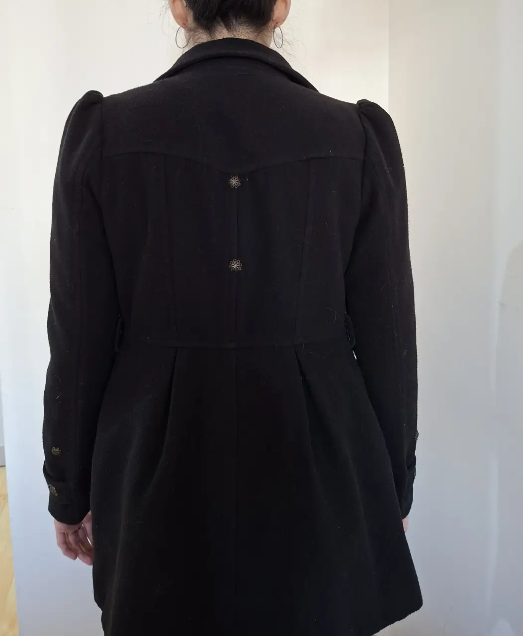Tapado negro de corte entallado con detalles de botones decorativos en la espalda. Manga corte pricesa, Ideal para un look elegante y abrigado.